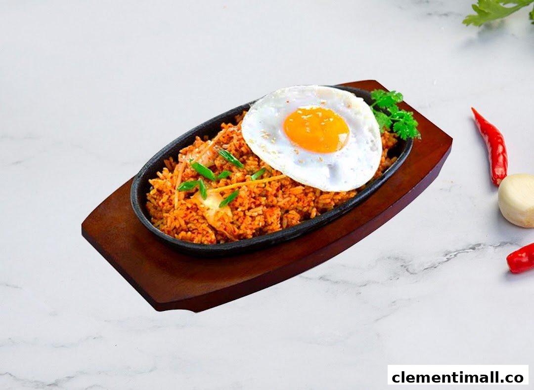 A sizzling plate of Korean fried rice topped with a perfectly cooked fried egg and fresh garnishes.