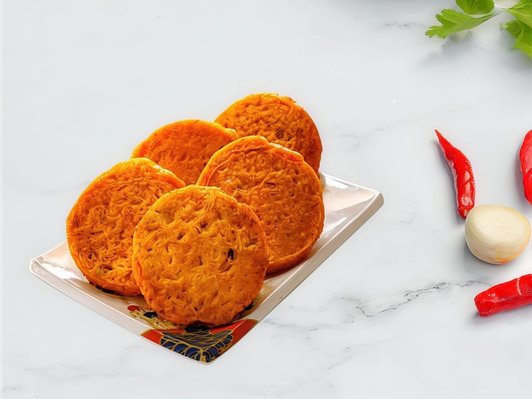 A plate of golden-brown Korean pancakes or fritters, with fresh chili, onion, and herbs.