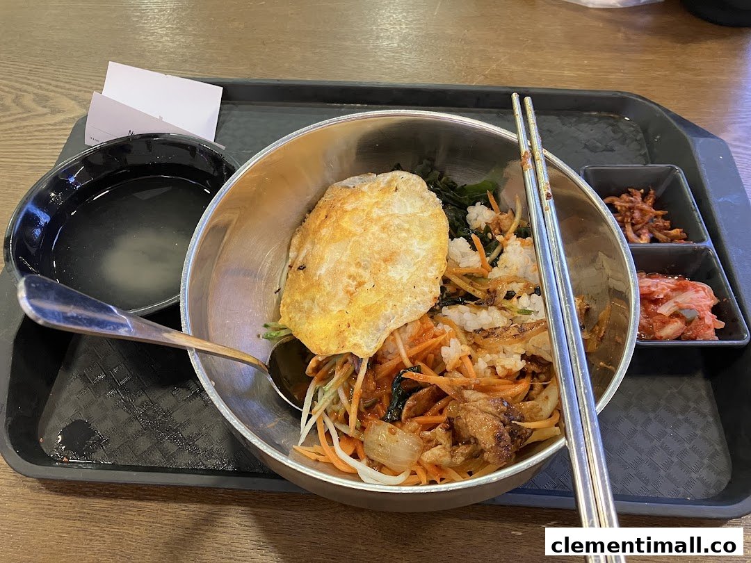 A vibrant bowl of Korean bibimbap with side dishes and soup on a tray.