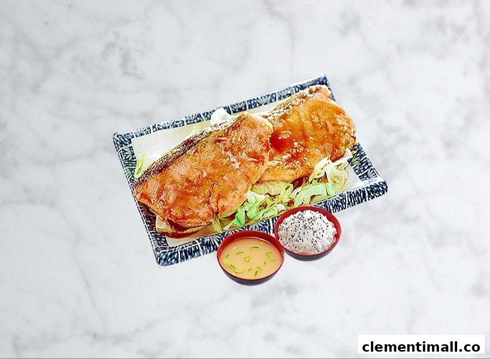 A delicious Korean-style fried fish dish served with rice and miso soup on a marble surface.