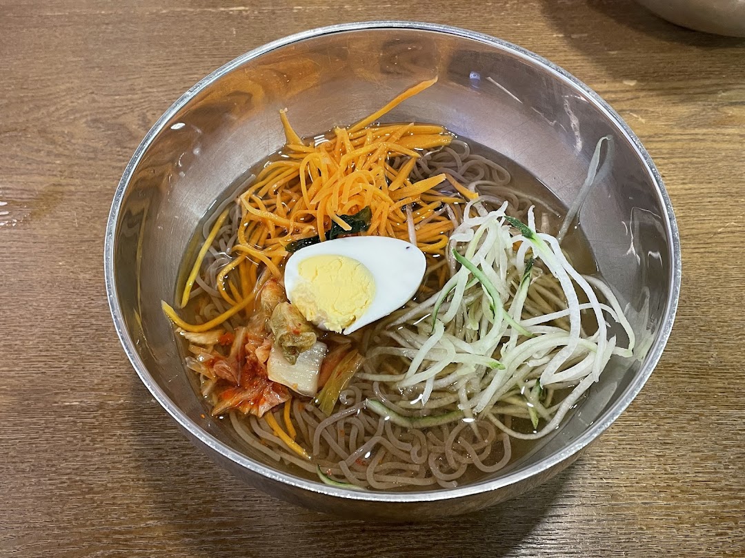 A refreshing bowl of Korean cold noodles (Naengmyeon) with egg, kimchi, and fresh vegetables.
