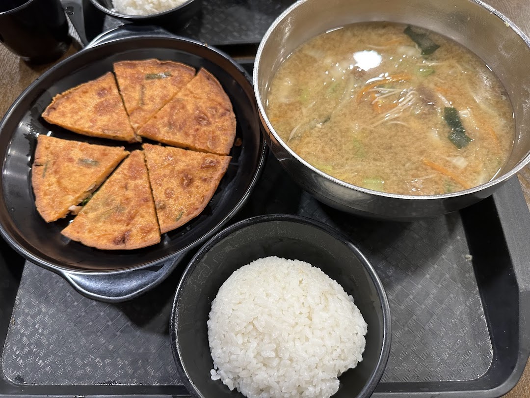A delicious Korean meal featuring a savory pancake, a bowl of rice, and a hearty soup.