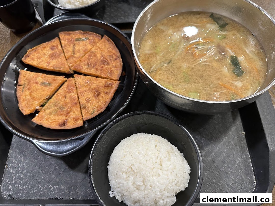 A delicious Korean meal featuring a savory pancake, a bowl of rice, and a hearty soup.