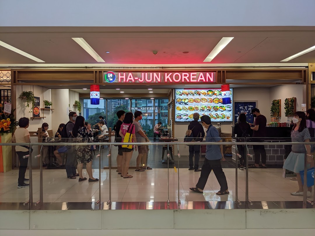 The bustling entrance of Ha-Jun Korean restaurant, featuring its signage, customers, and a digital menu board.