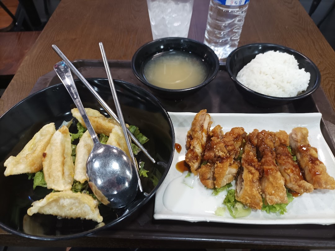 A delicious Korean meal featuring crispy fried chicken, dumplings, rice, and soup on a tray.