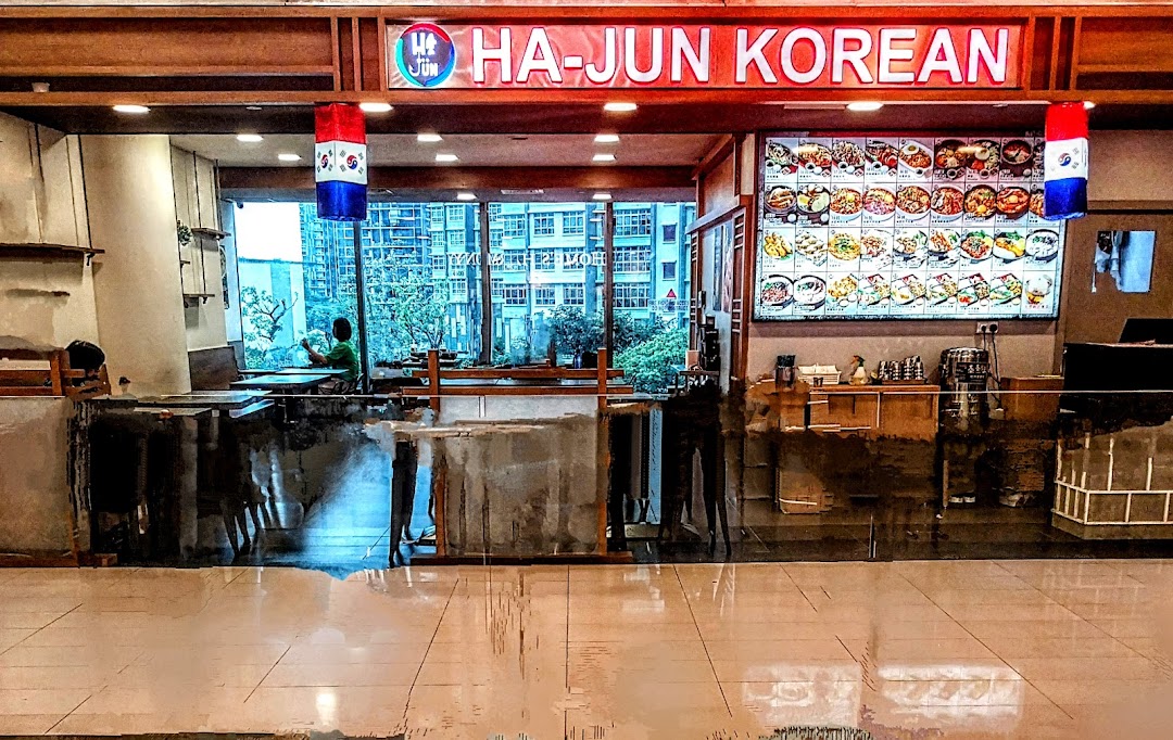 The inviting shop front of Ha-Jun Korean restaurant, featuring a vibrant menu display and comfortable seating.
