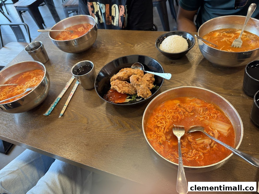 A table laden with several bowls of spicy Korean ramen, fried chicken, and rice at Ha-Jun Korean.