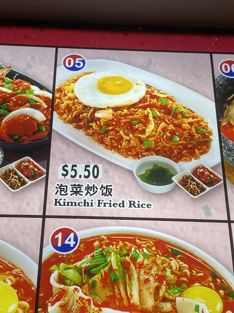 A menu display showing a vibrant plate of Kimchi Fried Rice with a fried egg and side dishes.
