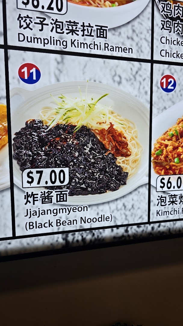 A digital menu board displaying various Korean noodle and rice dishes with prices.