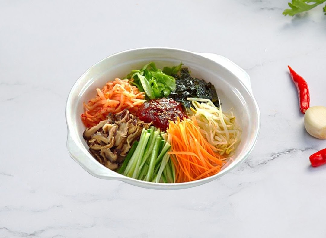 A vibrant bowl of Korean bibimbap featuring various fresh vegetables and gochujang.