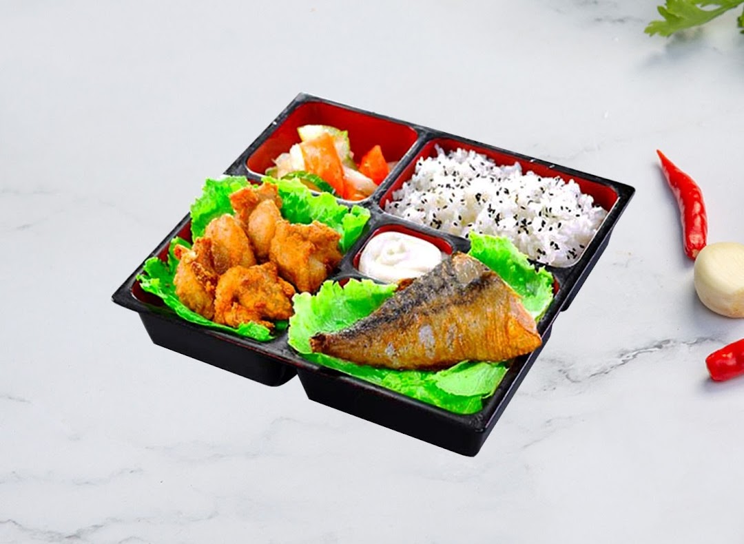 A delicious Korean bento box featuring fried chicken, grilled fish, rice, and pickled vegetables.