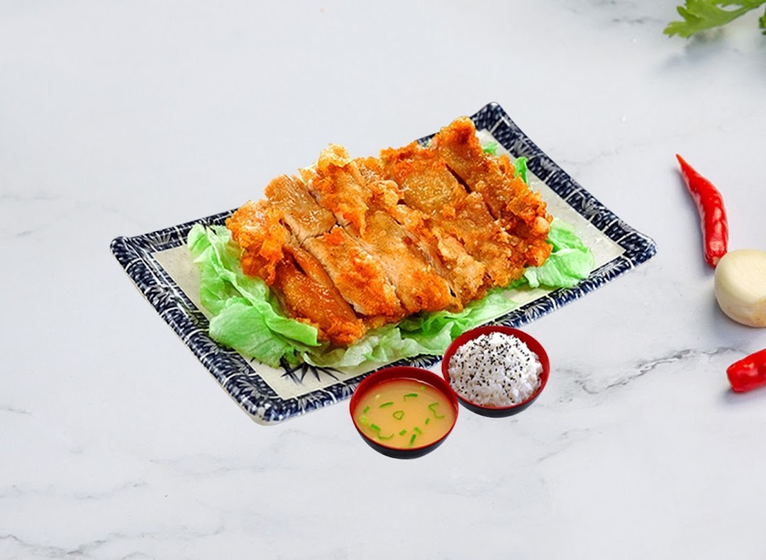 A plate of golden fried chicken with fresh lettuce, served with rice and miso soup.