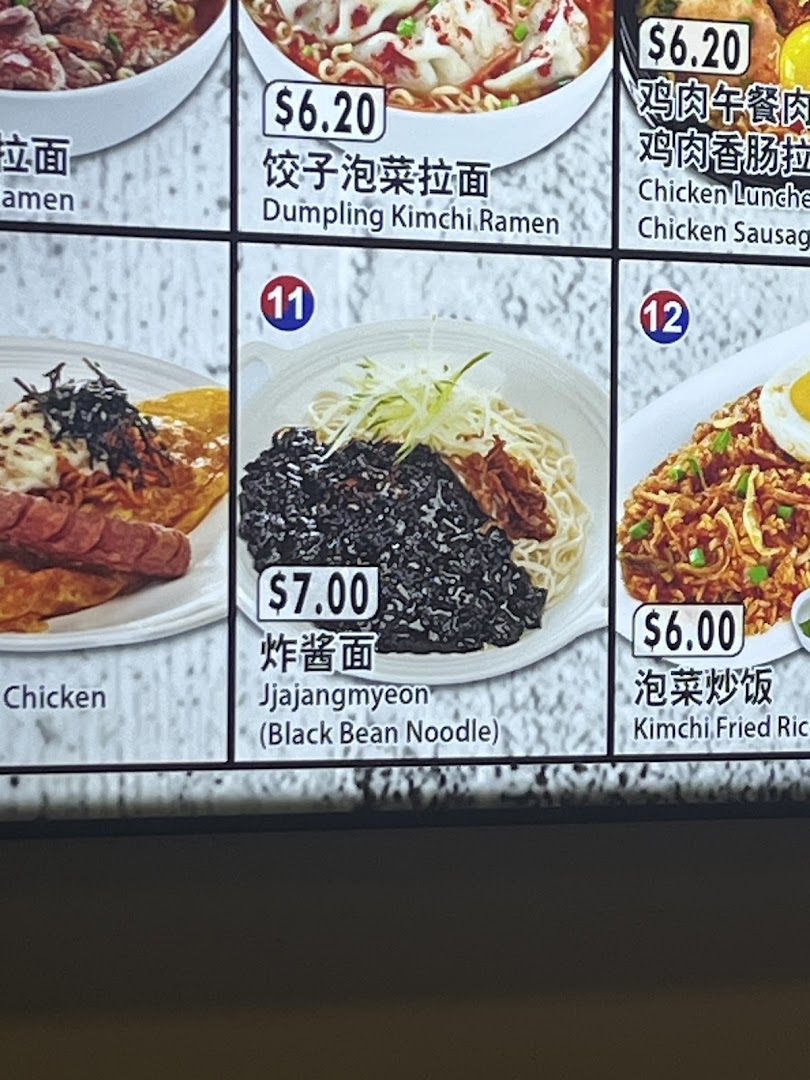 A close-up of a digital menu board displaying various Korean noodle and rice dishes with prices.