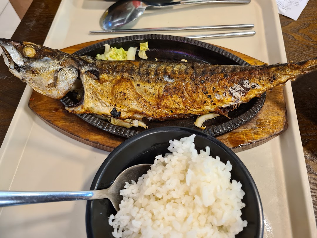 A perfectly grilled whole fish served on a sizzling plate with a side of white rice.