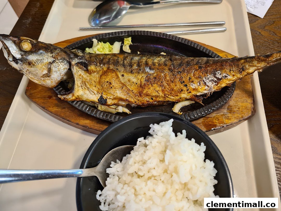 A perfectly grilled whole fish served on a sizzling plate with a side of white rice.