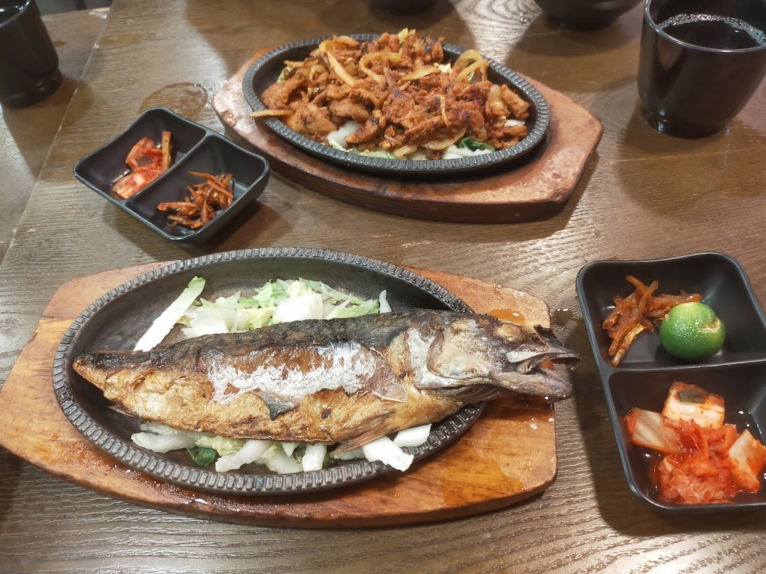 A table laden with delicious Korean dishes, including grilled fish, spicy pork, and traditional banchan.