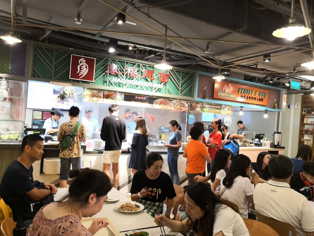 Diners enjoy meals at a bustling food court, featuring the HAO Local Delight Hokkien Mee stall.