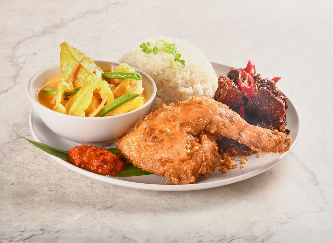 A delicious plate featuring fragrant rice, crispy fried chicken, a rich curry, and spicy sambal.