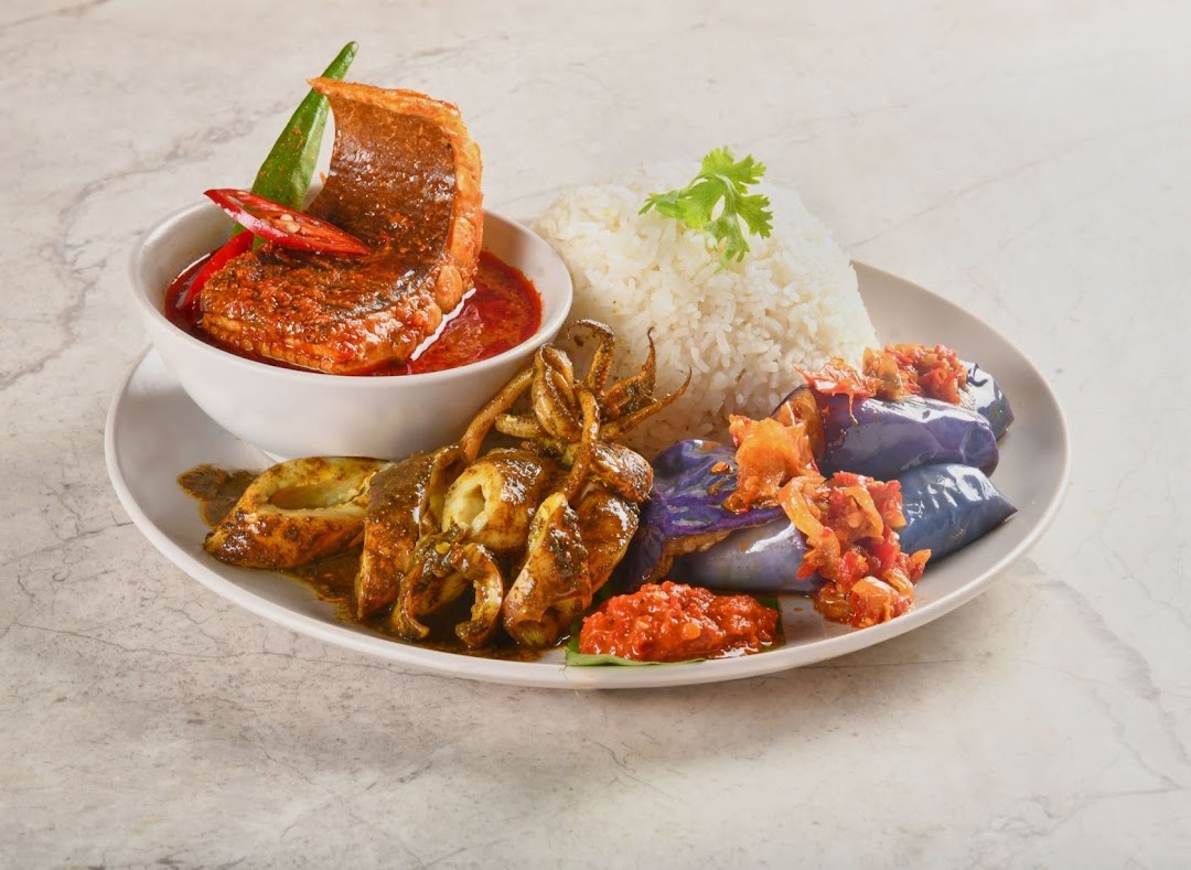 A vibrant plate featuring rice, fish curry, grilled squid, and eggplant with sambal, showcasing a traditional Malay meal.