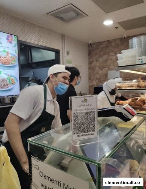 Friendly staff at Hjh Maimunah Mini serving customers, with a digital menu board in the background.
