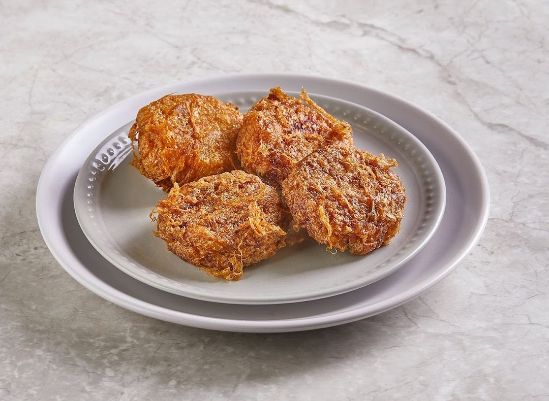 Four golden-brown fried patties or fritters are presented on two stacked grey plates.