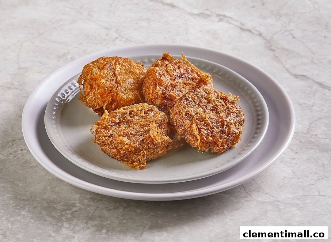 Four golden-brown fried patties or fritters are presented on two stacked grey plates.