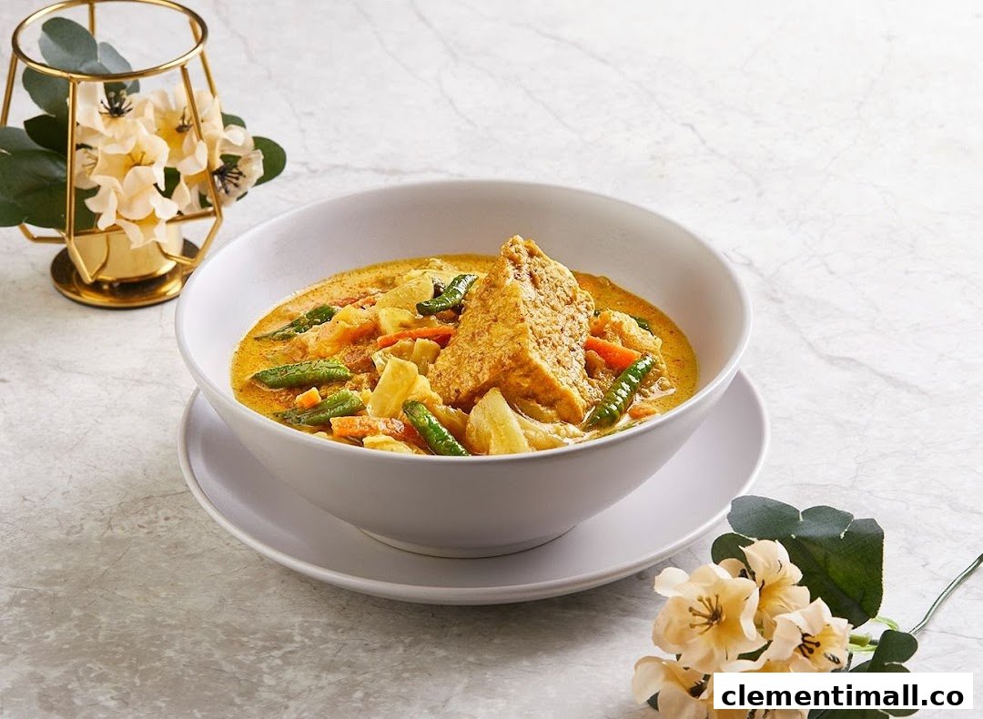 A vibrant bowl of yellow curry or stew with vegetables and a large piece of fried tofu.