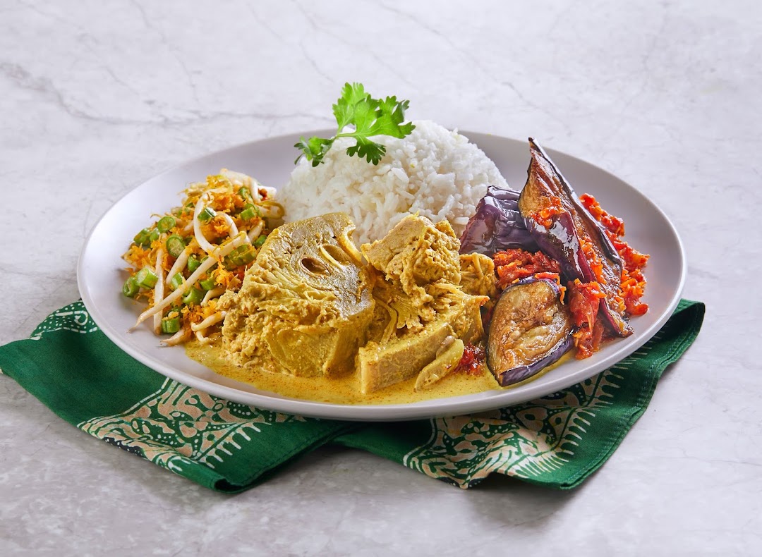A plate of traditional Malay cuisine with rice, jackfruit curry, eggplant sambal, and bean sprout salad.
