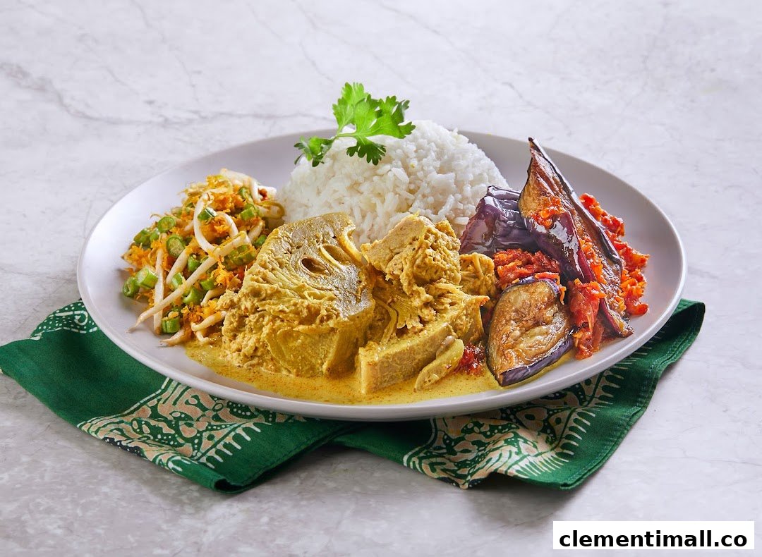A plate of traditional Malay cuisine with rice, jackfruit curry, eggplant sambal, and bean sprout salad.