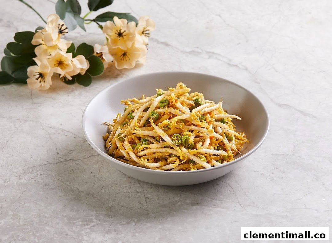 A bowl of stir-fried bean sprouts with green chilies and a yellow sauce, garnished with flowers.