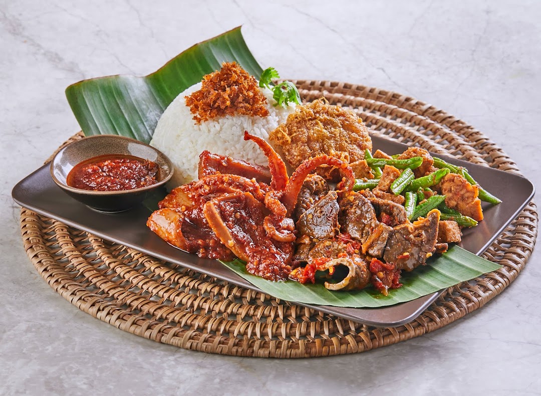 A vibrant platter of traditional Malay/Indonesian cuisine featuring rice, various meats, vegetables, and sambal.