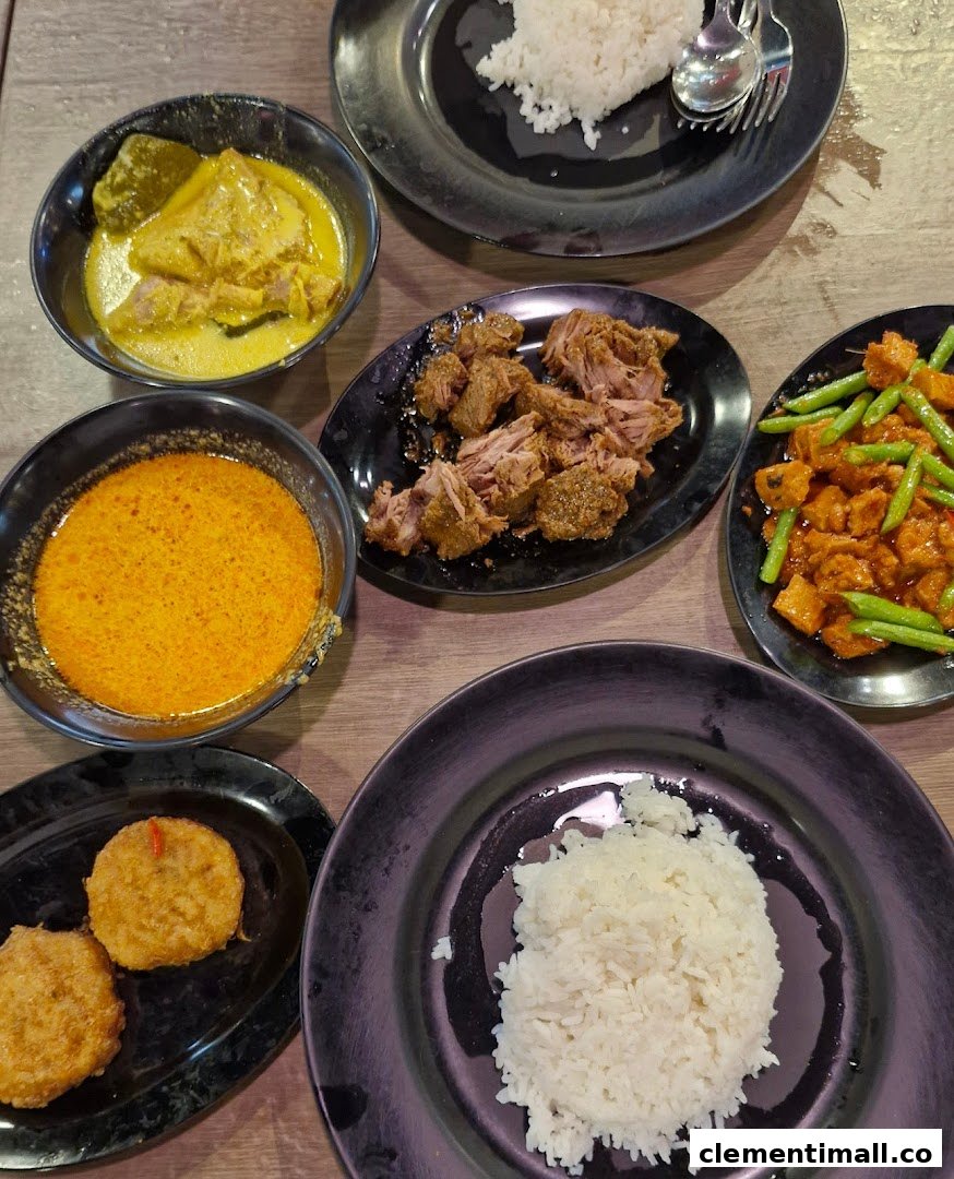 A vibrant spread of traditional Malay dishes, including rice, curries, and fried items, on a wooden table.