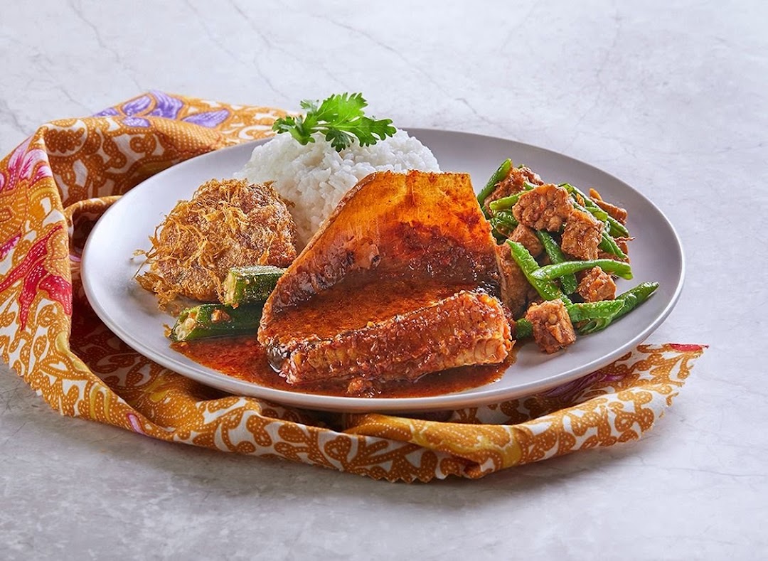 A plate of traditional Malay/Indonesian food featuring rice, fish in curry, fried egg, and stir-fried vegetables.