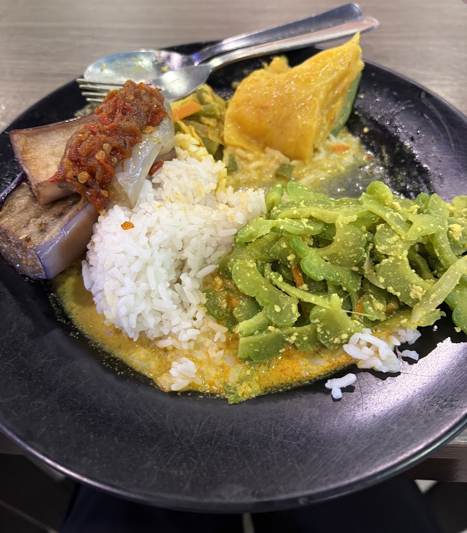 A plate of traditional Malay rice with bitter gourd, eggplant sambal, and a yellow vegetable.