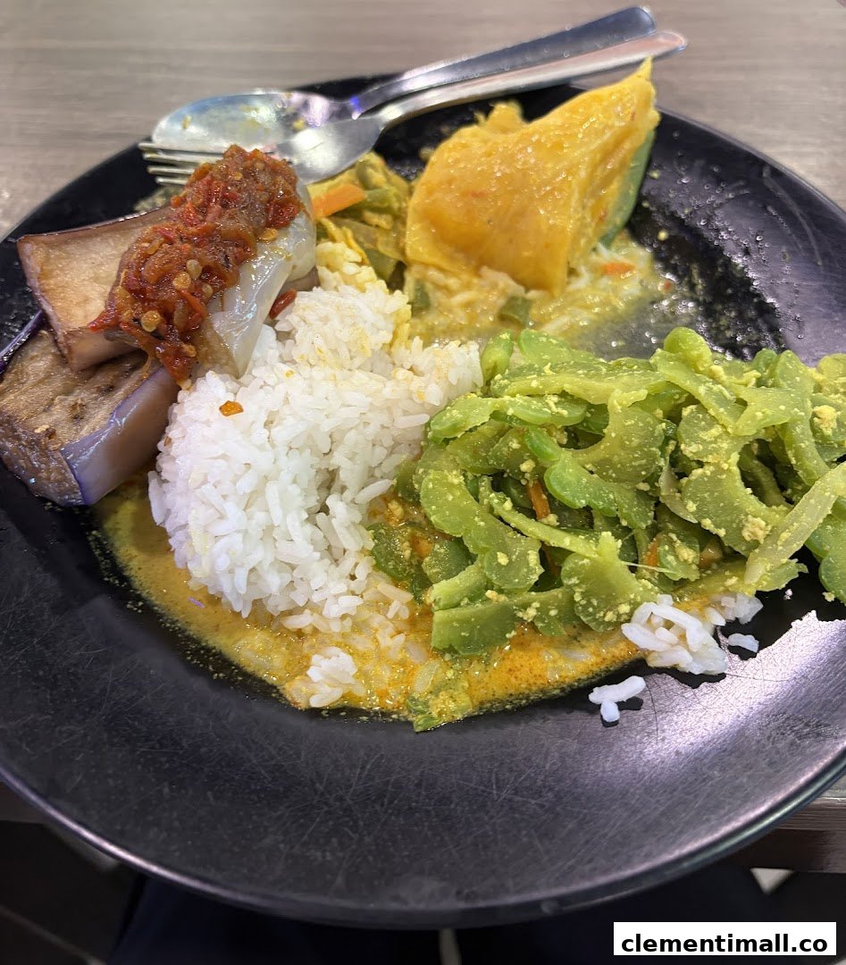 A plate of traditional Malay rice with bitter gourd, eggplant sambal, and a yellow vegetable.