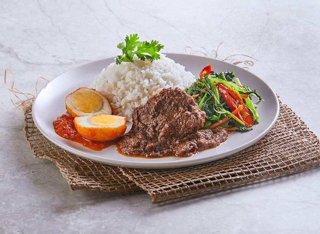 A delicious plate of traditional Malay/Indonesian food featuring rice, beef rendang, fried egg, and stir-fried vegetables.