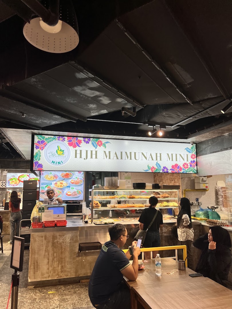 Interior view of Hjh Maimunah Mini, a bustling food stall with customers, staff, and a variety of dishes on display.