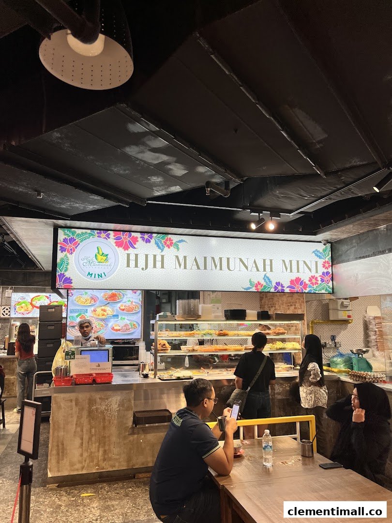 Interior view of Hjh Maimunah Mini, a bustling food stall with customers, staff, and a variety of dishes on display.