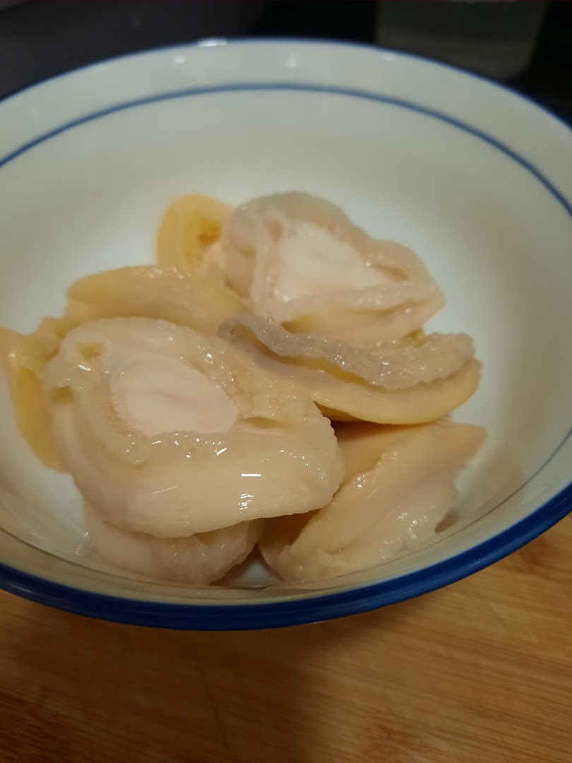 A close-up of tender, sliced abalone or similar tonic ingredients in a white bowl.