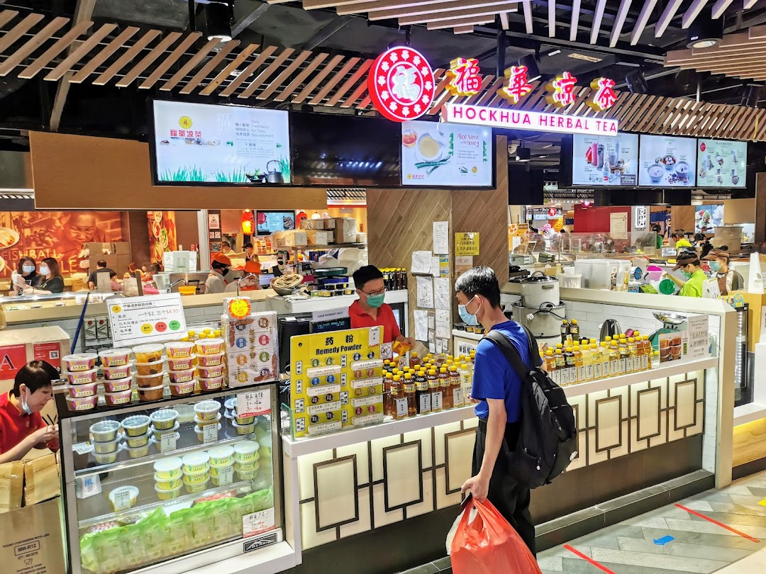 A customer at Hockhua Tonic's counter, surrounded by various herbal products and bottled drinks.