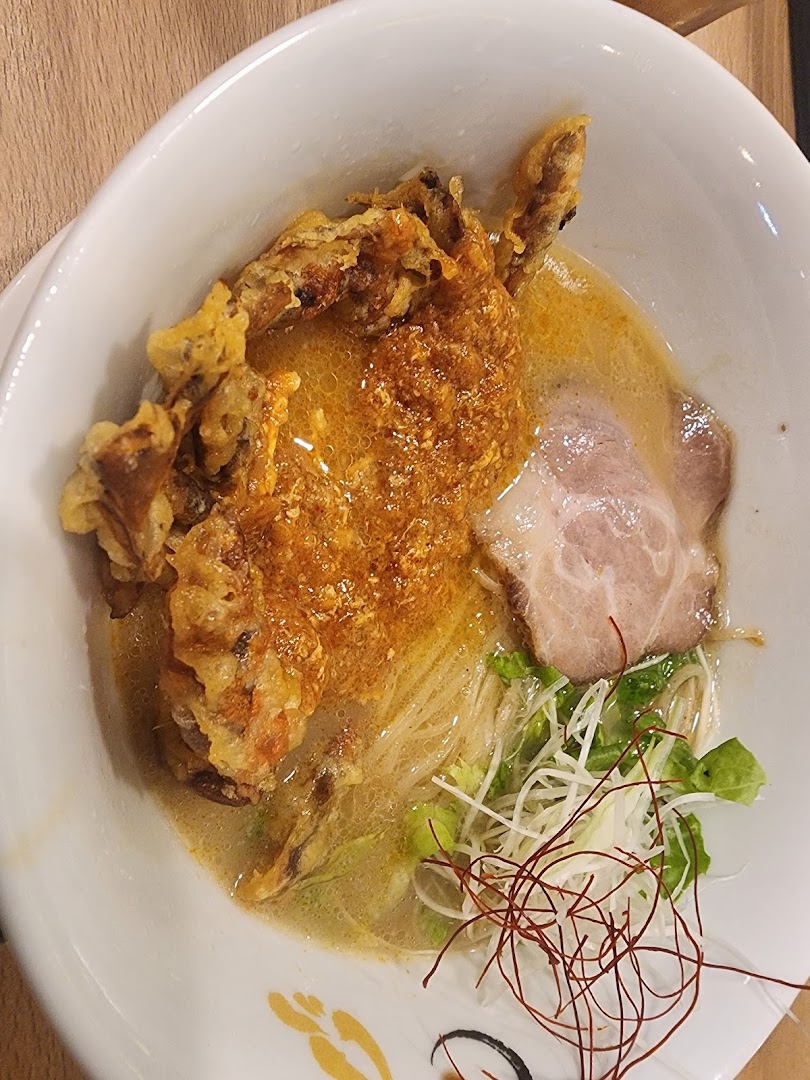 A close-up of a delicious ramen bowl featuring crispy soft-shell crab, chashu, and fresh garnishes.