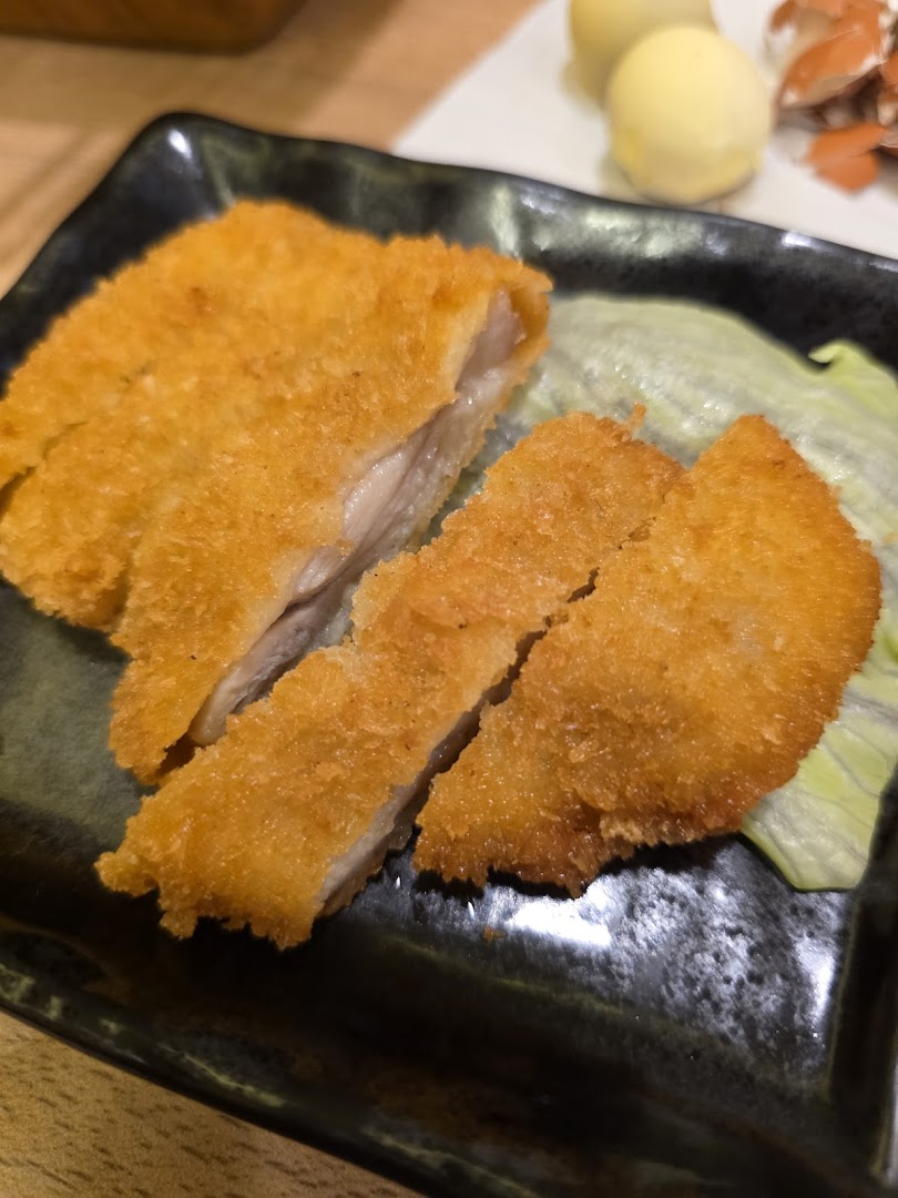 Crispy golden-brown fried cutlet, sliced and served on a dark plate with fresh lettuce.