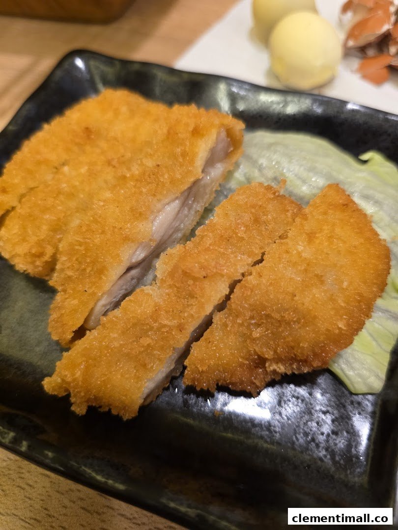 Crispy golden-brown fried cutlet, sliced and served on a dark plate with fresh lettuce.