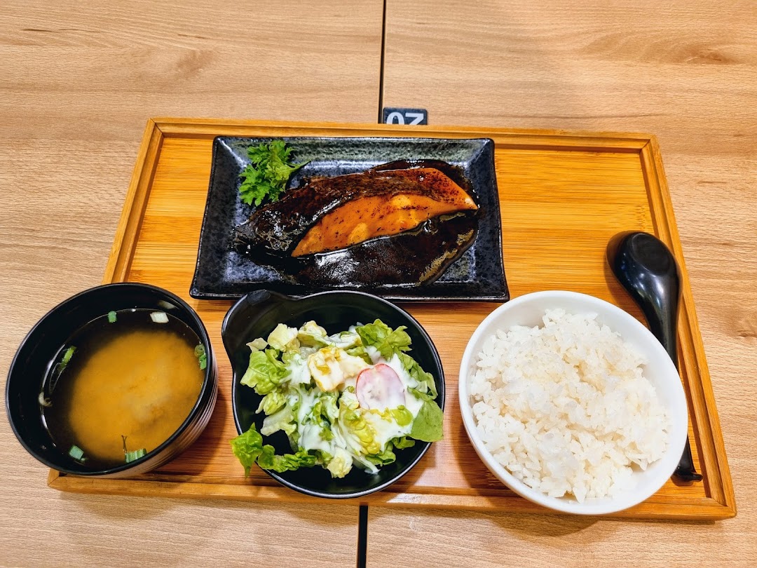 A delicious Japanese set meal featuring grilled fish, rice, salad, and miso soup on a wooden tray.