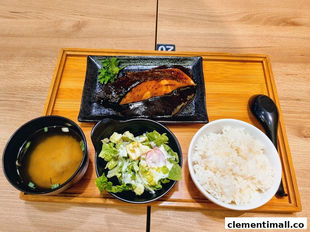 A delicious Japanese set meal featuring grilled fish, rice, salad, and miso soup on a wooden tray.