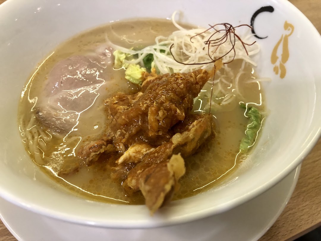 A close-up of a delicious ramen bowl featuring rich broth, noodles, pork chashu, and crispy fried chicken.