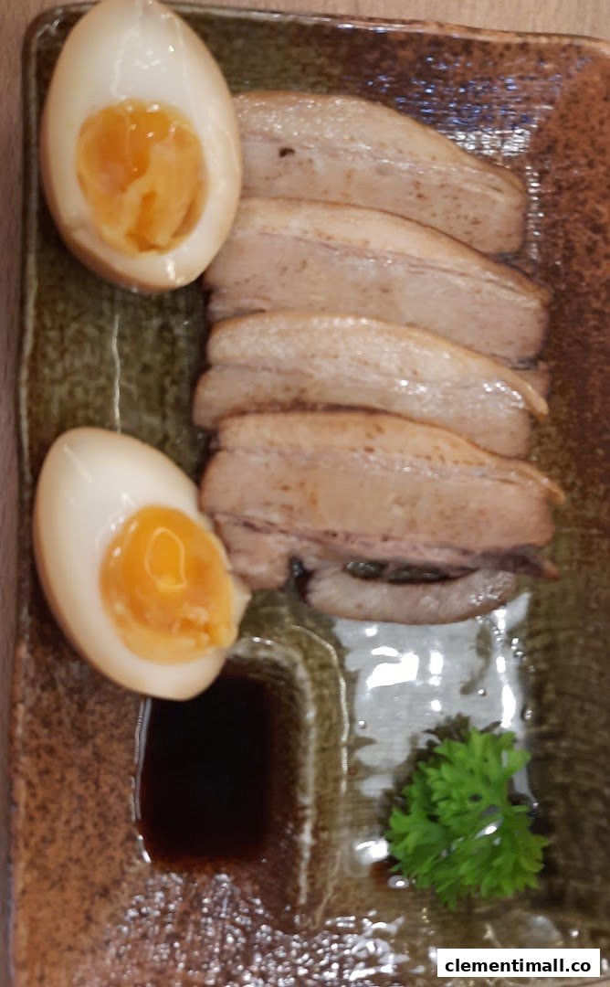 A close-up of a delicious side dish featuring tender pork belly slices and perfectly cooked soft-boiled eggs.