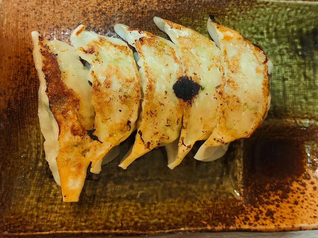 Close-up of perfectly pan-fried gyoza served on a rustic ceramic plate.