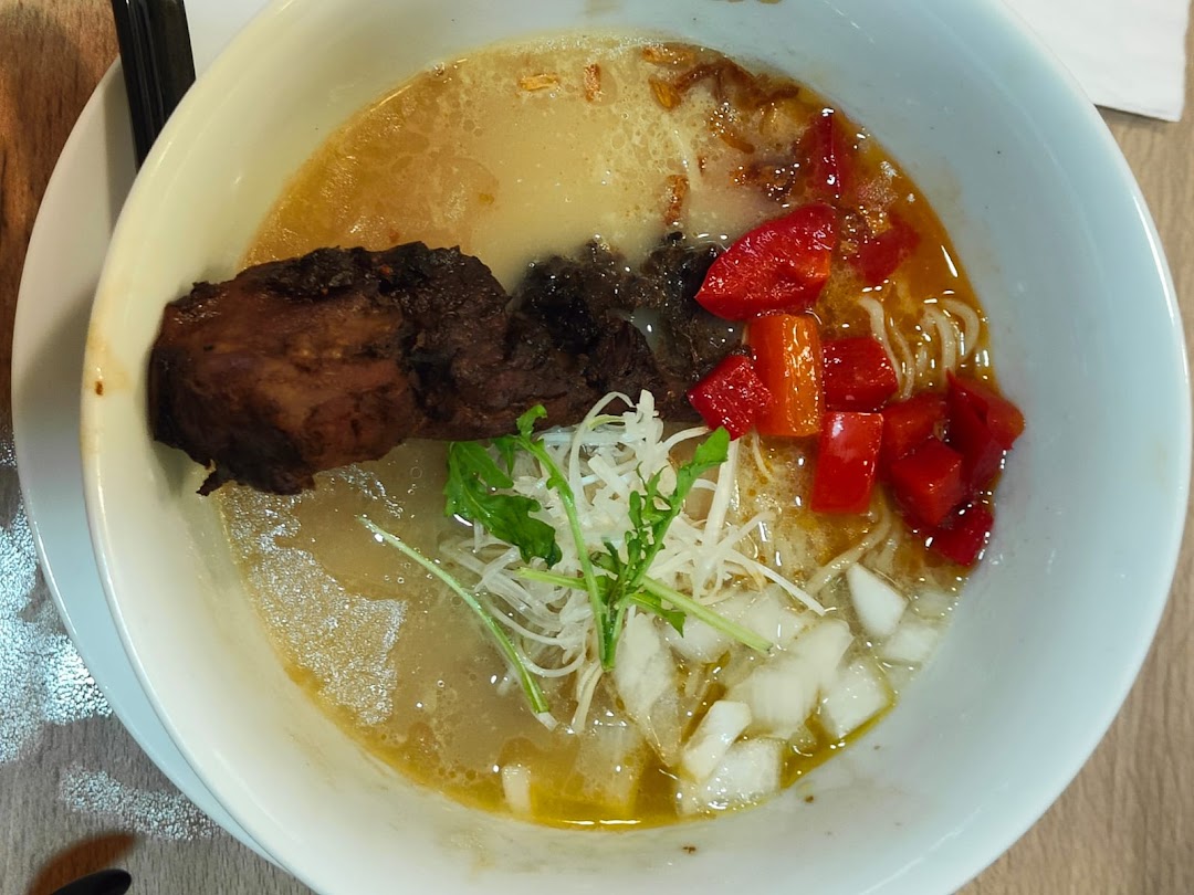 A close-up of a delicious ramen bowl featuring rich broth, tender meat, and fresh toppings.