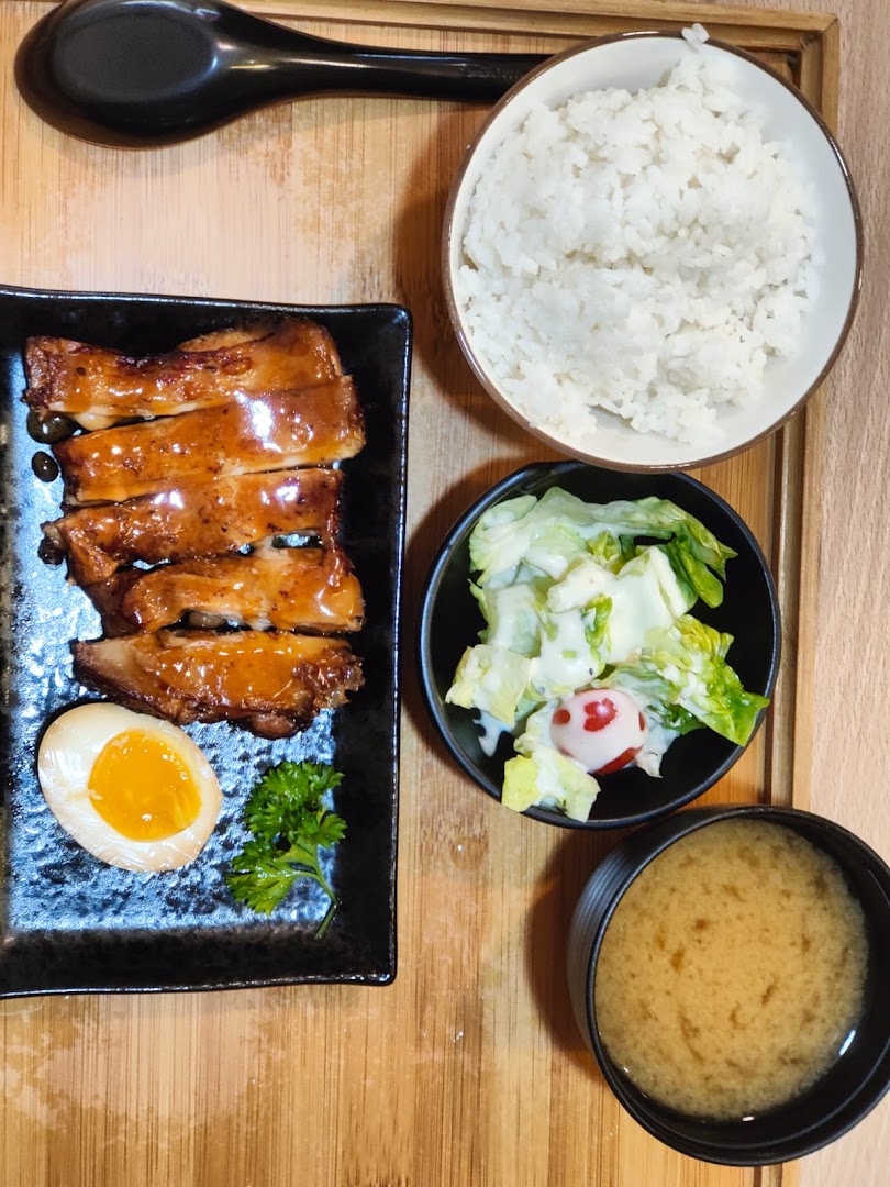 A delicious Japanese meal set featuring glazed chicken, rice, salad, miso soup, and a ramen egg.